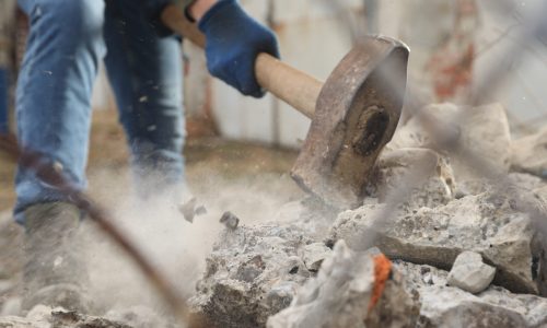 Man breaking stones with sledgehammer outdoors, closeup